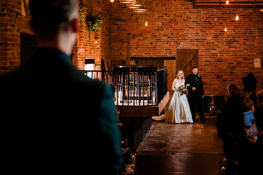 Bride walking down a barn aisle with her dad
