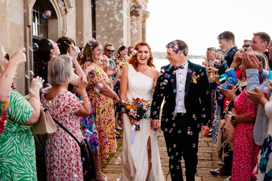 Couple walking through a cloud of bubbles after their ceremony