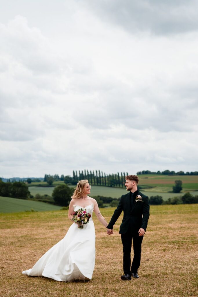 Couple walking hand in hand across Leicestershire fields