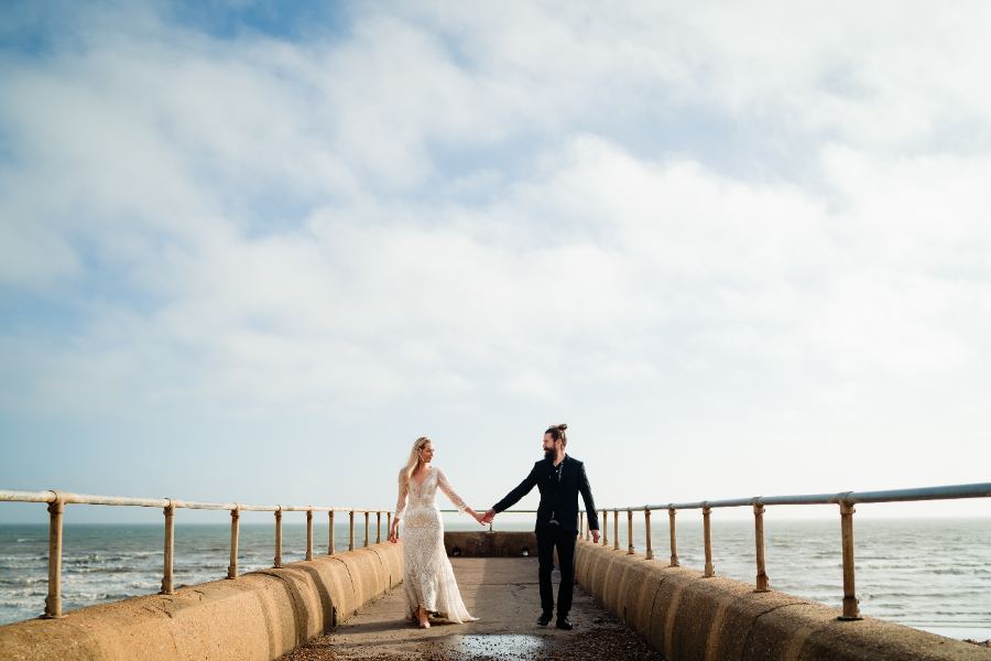 Couple walking hand in hand along a sea wall