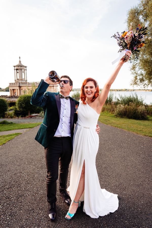 Groom swigging from a bottle, bride cheering with her bouquet