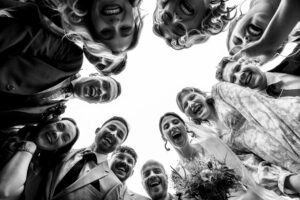 Wedding party huddled round the camera, laughing